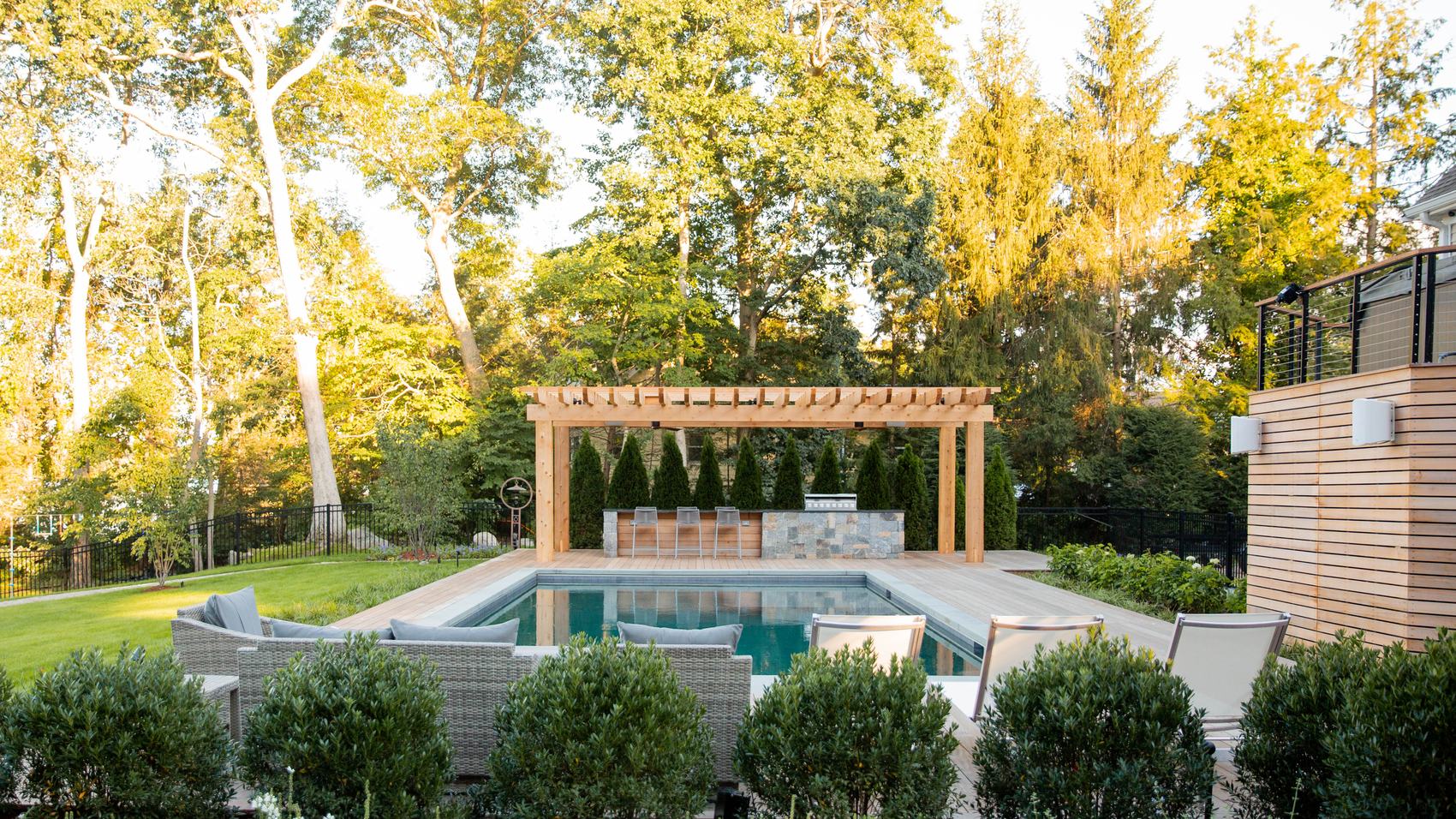 Sharon Landscape — cedar pergola and stone outdoor kitchen mirrored in the pool