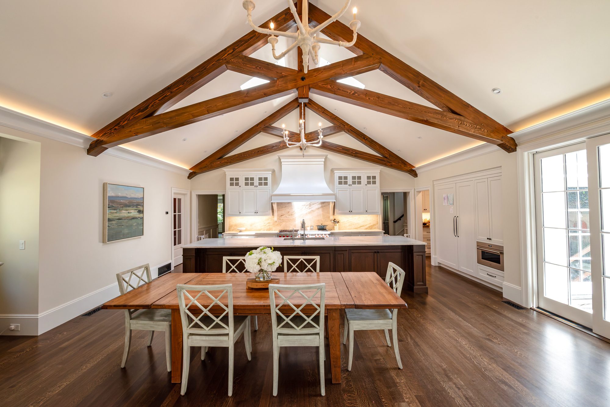 Wellesley Renovation — custom kitchen beneath a beamed cathedral ceiling, viewed across the dining table