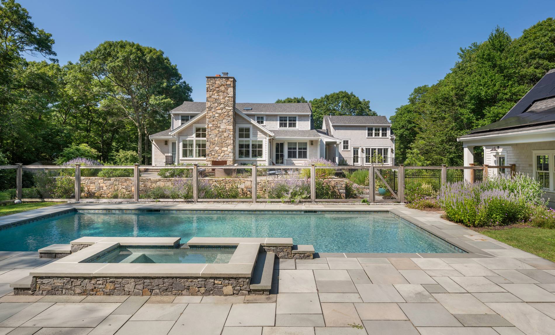Westport Residence — pool and spa on the bluestone terrace, with the renovated rear elevation and stone chimney beyond